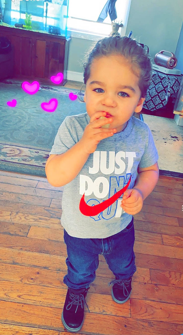 Joèl is registered to the contest to win money with this photo: arm, baby_toddler_clothing, blue, cheek, chin, eye, face, hair, hairstyle, hand, happy, head, joint, nose, organ, person, shirt, skin, sleeve, standing