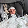 baby, newborn, sleeping, car_seat, blanket, plush_toy, bunny, hat, infant, cozy, child, soft, cute, indoors, resting, comfort, fabric, star_pattern, peaceful, nap