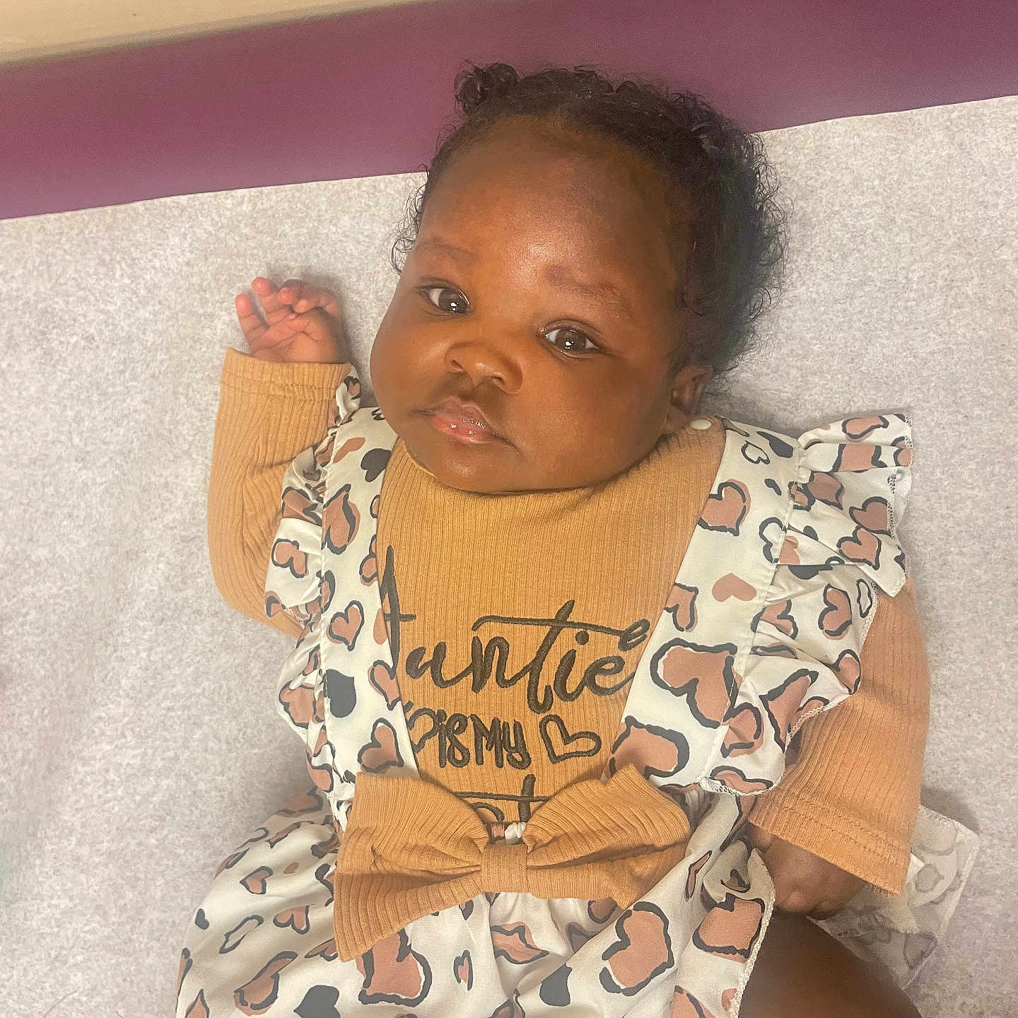 Kendal joined the competition — help win amazing prizes! baby, infant, child, face, clothing, patterned_dress, heart_pattern, hair_buns, lying_down, soft_surface, mustard_top, cute, adorable, portrait, skin, expression, indoor, person, young, fashion