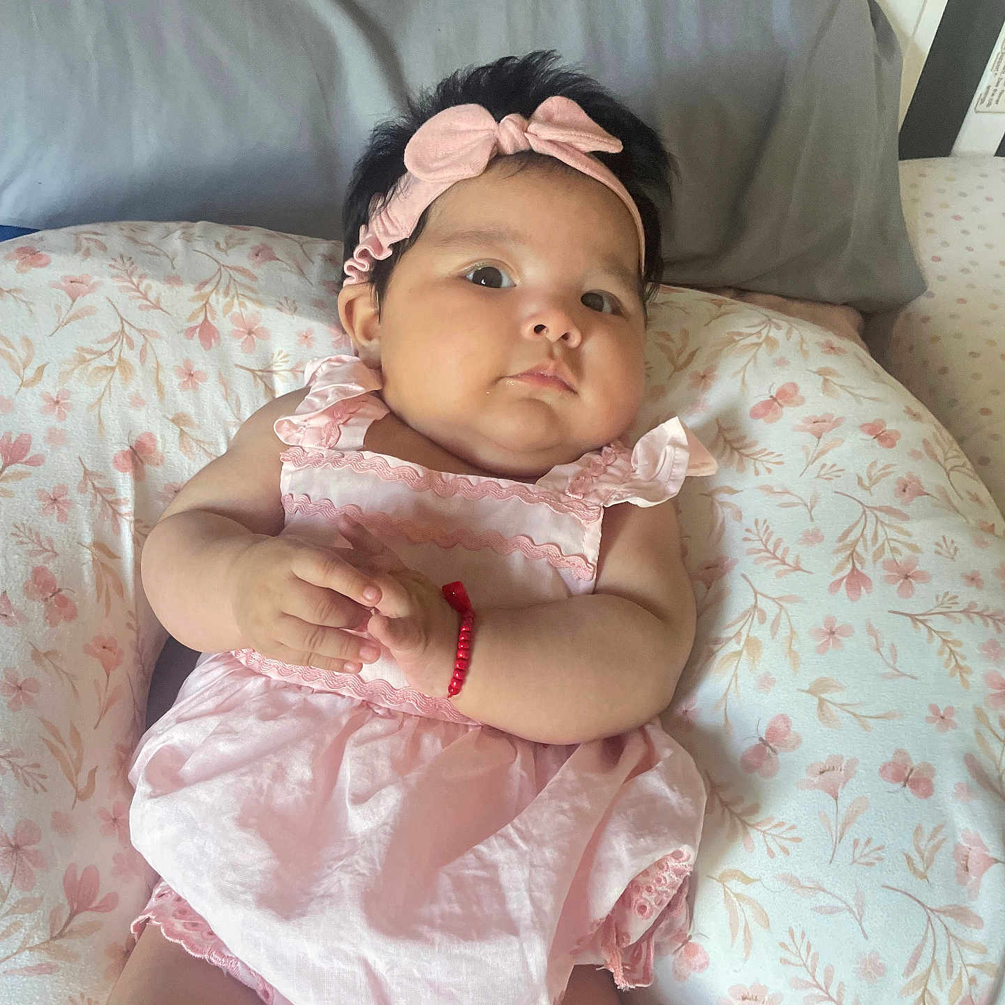 Jessenia joined the competition — help win amazing prizes! baby, infant, pink_dress, headband, bracelet, floral_cushion, cute, indoors, portrait, child, skin, face, hands, lying_down, soft_light, plush, cozy, adorable, resting, young_child