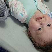 Gracie is registered to the contest to win money with this photo: baby, bed, blanket, cheek, child, closeup, eyes, face, hair, infant, lying_down, mattress, mouth, onesie, pillow, skin, smile, striped_pillow, striped_sheet, teeth