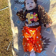 Rai'Vyn joined the competition — help win amazing prizes! baby, child, infant, outdoor, blanket, grass, orange_clothing, brown_clothing, headband, bow, first_thanksgiving, socks, flower, patterned_blanket, celebration, festive, thanksgiving, cute, portrait, lying_down