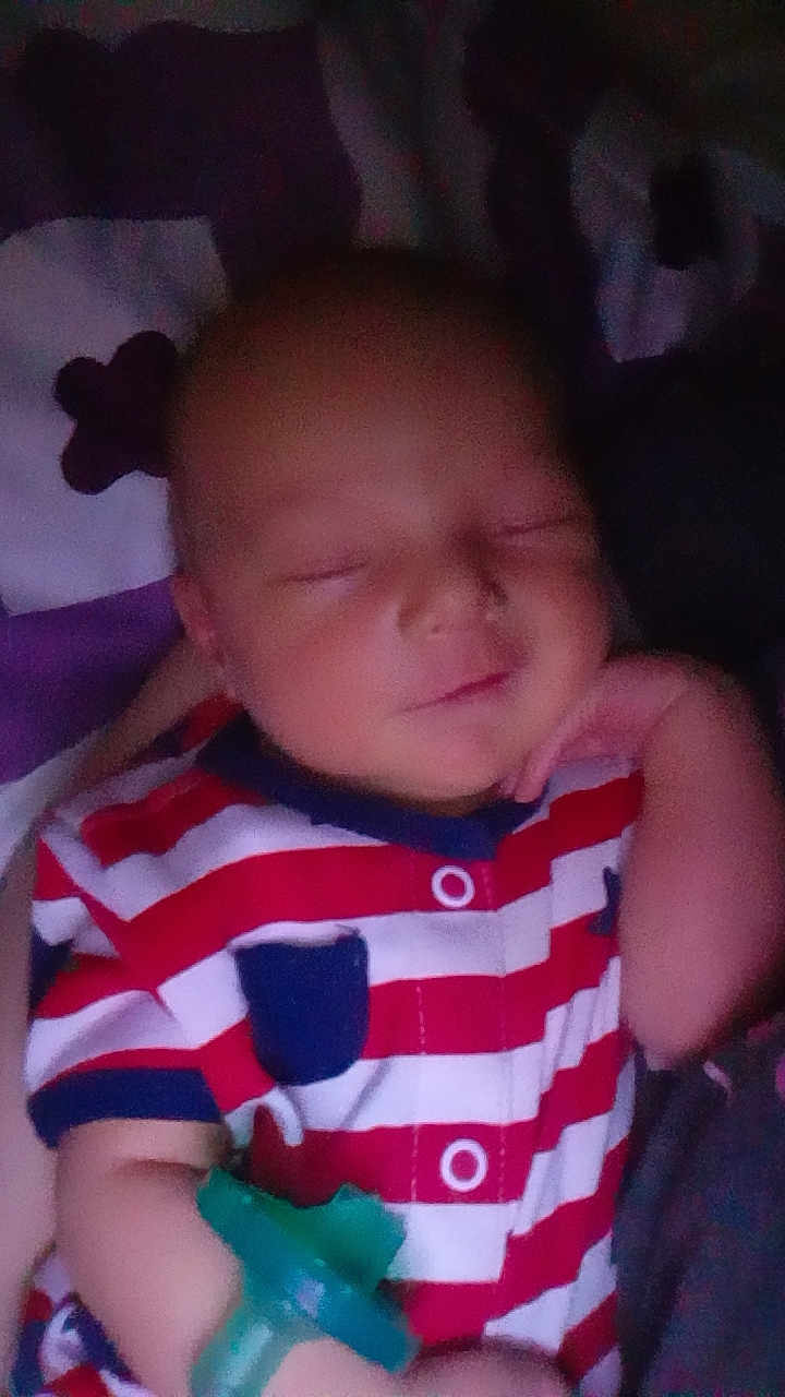 Waylon is registered to the contest to win money with this photo: baby, infant, sleeping, striped_clothing, romper, pacifier, hand, arm, pillow, blanket, red_white_stripes, navy_blue, newborn, portrait, closeup, indoor, soft_lighting, peaceful, face, nursery