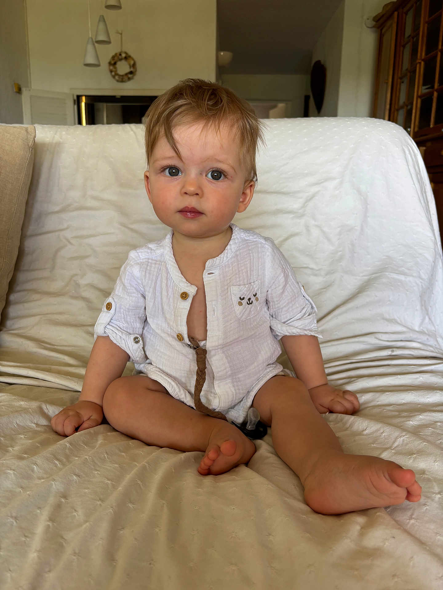 Lino a rejoint le concours — aidez-le/la à gagner de superbes lots ! baby, child, couch, cute, expression, eyes, face, feet, furniture, hair, hands, home, indoor, innocent, pacifier, portrait, room, sitting, toddler, white_clothing