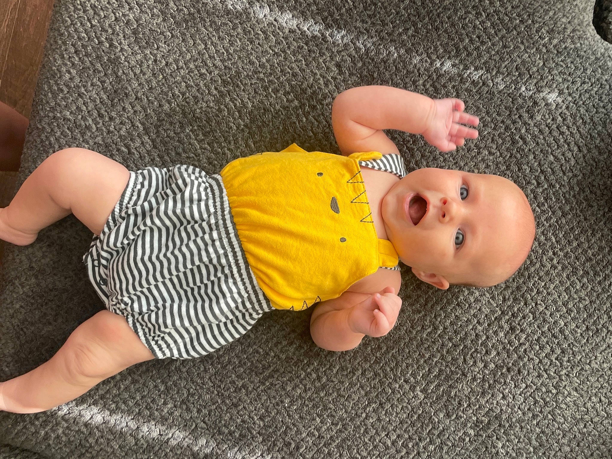 Charley is registered to the contest to win money with this photo: baby, baby_toddler_clothing, cheek, child, comfort, finger, floor, flooring, foot, head, human_body, joint, leg, linens, mammal, person, skin, sock, thigh, toddler