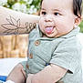 Giovanne joined the competition — help win amazing prizes! baby, child, infant, tongue_out, green_outfit, tattoo, arm, sitting, cute, outdoor, nature, skin, face, expression, happy, soft_light, closeup, person, sock, summer