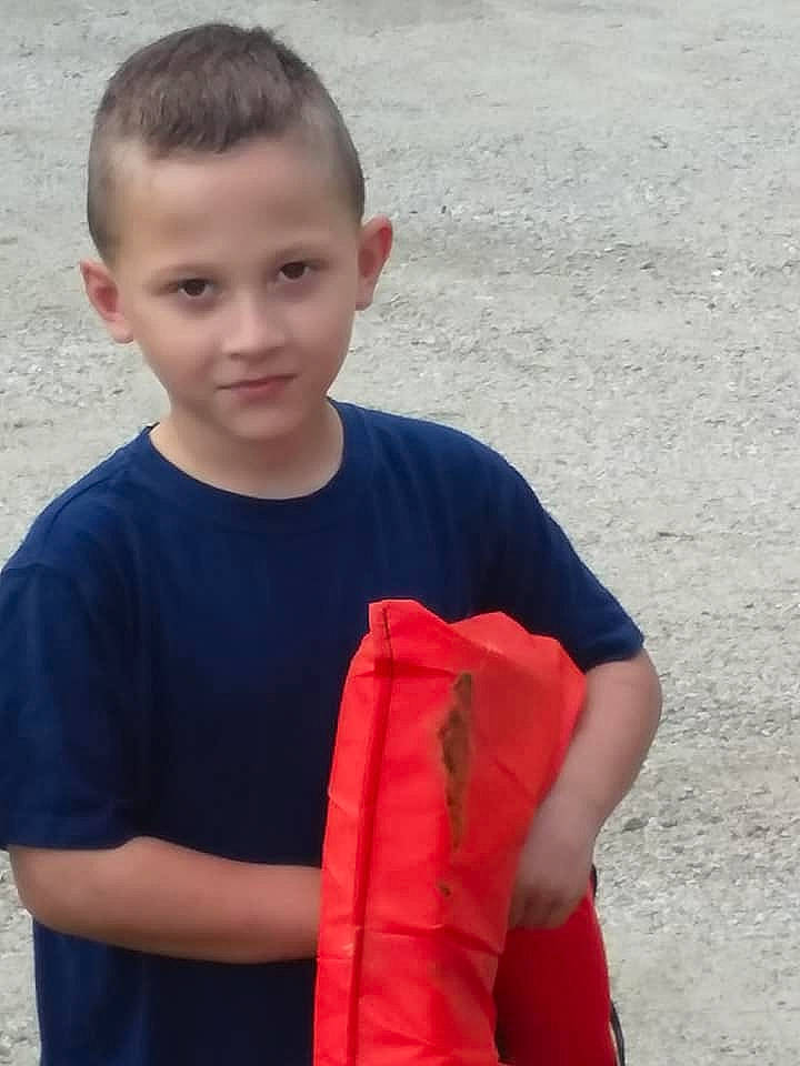 Clifford is registered to the contest to win money with this photo: arm, child, elbow, joint, lifejacket, person, personal_protective_equipment, play, red, shoulder, sleeve, standing, t_shirt, toddler, vacation