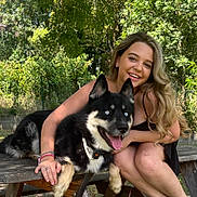 Koda a rejoint le concours — aidez-le/la à gagner de superbes lots ! woman, dog, outdoor, picnic_table, smiling, happy, nature, greenery, tree, pet, animal, casual, summer, friendship, fur, collar, portrait, bench, leisure, daylight