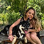 woman, dog, outdoor, picnic_table, smiling, happy, nature, greenery, tree, pet, animal, casual, summer, friendship, fur, collar, portrait, bench, leisure, daylight