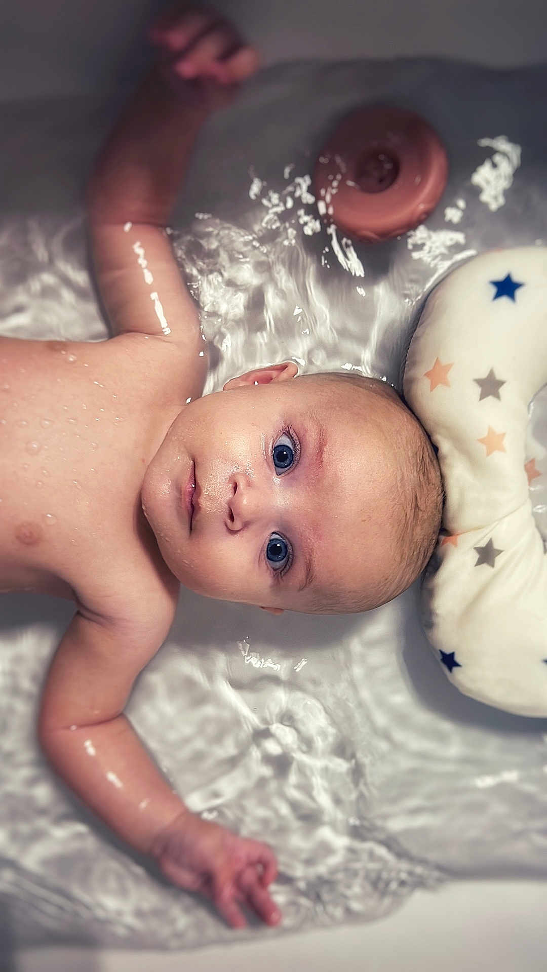 Ezra participe au concours pour gagner de l'argent avec cette photo : baby, water, bath, floating, blue_eyes, skin, arm, hand, pillow, stars, infant, child, relaxing, wet, face, portrait, closeup, tub, cute, peaceful