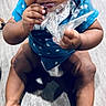 baby, child, blue_clothing, polka_dot, floor, wooden_floor, sitting, curious, chewing, plastic, hands, legs, toes, indoors, person, infant, cute, expression, large_eyes, skin
