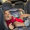 baby, car_seat, infant, child, red_clothing, socks, vehicle, interior, seat, safety, window, sunlight, young_child, portrait, seatbelt, headrest, casual, relaxed, young, indoors