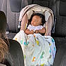 baby, car_seat, blanket, child, car_interior, seat, infant, vehicle, child_safety, person, seatbelt, upholstery, headrest, pattern, colorful, transportation, travel, cute, young_child, portrait