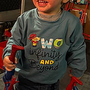 Jaxson is registered to the contest to win money with this photo: toddler, child, smiling, indoor, toy, action_figure, superhero, clothing, sweatshirt, jeans, play, happy, person, young_child, holding, fun, cute, portrait, colorful, imagination