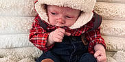 Woodson joined the competition — help win amazing prizes! baby, infant, plaid_jacket, hood, brown_socks, denim_pants, blanket, soft_texture, cozy, cute, child, sitting, indoors, warm_clothing, face, small_hands, fur_trim, casual_wear, portrait, young