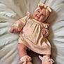 baby, infant, smiling, headband, dress, shoes, blanket, feathers, soft_colors, cute, happy, lying_down, indoors, portrait, child, person, fashion, footwear, apparel, toddler