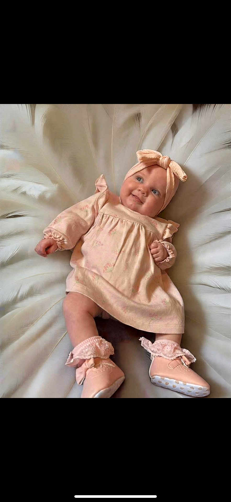 Ayla-Louise is registered to the contest to win money with this photo: baby, infant, smiling, headband, dress, shoes, blanket, feathers, soft_colors, cute, happy, lying_down, indoors, portrait, child, person, fashion, footwear, apparel, toddler
