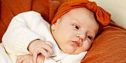 Kaislee is registered to the contest to win money with this photo: baby, infant, blanket, headband, bow, white_clothing, hands, face, skin, sleepwear, cute, portrait, newborn, child, resting, indoors, soft_texture, warm_colors, expression, closeup