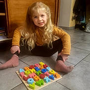 Sun a rejoint le concours — aidez-le/la à gagner de superbes lots ! child, blonde_hair, sitting, floor, puzzle, alphabet, toy, colorful, socks, sweater, indoor, tiles, young, smiling, playtime, person, home, wooden_furniture, long_hair, casual_clothing