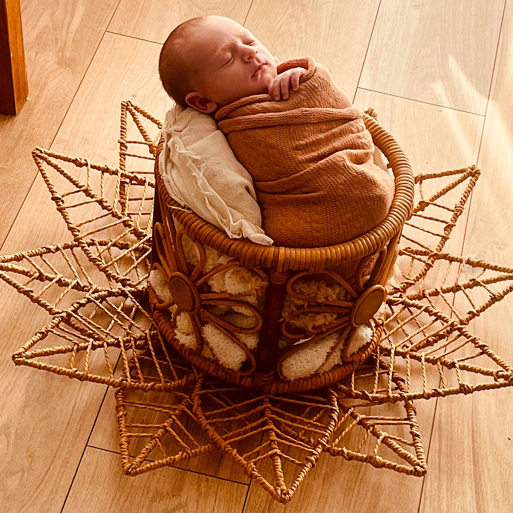 Alessio participe au concours pour gagner de l'argent avec cette photo : newborn, baby, sleeping, wrapped, blanket, basket, woven, wooden_floor, decorative, cozy, peaceful, indoors, soft_light, infant, resting, portrait, cute, child, warm_tones, texture