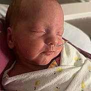 Avyn is registered to the contest to win money with this photo: baby, newborn, infant, sleeping, swaddle, blanket, feeding_tube, hospital, bassinet, portrait, closeup, peaceful, cheek, nose, mouth, head, pink, white, nursery, medical_tape