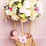 newborn, baby, sleeping, flower_arrangement, burlap, basket, headband, pink_background, pastel_colors, decorative_flowers, soft_texture, cute, infant, studio_photography, floral, peaceful, resting, portrait, props, creative