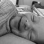 baby, newborn, sleeping, smile, closeup, blanket, swaddle, portrait, black_and_white, cheek, nose, eyelids, soft_texture, cozy, indoor, resting, toddler_like, peaceful, nursery, fabric