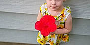 Adalynn joined the competition — help win amazing prizes! blue_eyes, child, curly_hair, cute, flip_flops, flower, girl, grass, hair_bun, hibiscus, holding_flower, outdoor, playful, polka_dot_leggings, portrait, red_hair, siding_wall, smile, standing, sunflower_dress