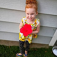Adalynn joined the competition — help win amazing prizes! child, girl, redhead, hair_bun, smile, flower, red_flower, hibiscus, dress, sunflower_pattern, polka_dot_leggings, flip_flops, grass, backyard, house_siding, portrait, standing, happy, outdoor, cute