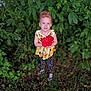 child, red_flower, hibiscus, sunflower_top, polka_dot_leggings, flip_flops, greenery, leaves, grass, outdoor, portrait, smile, blue_eyes, red_hair, hair_bun, standing, holding, nature, cute, toddler