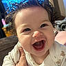 baby, baby_girl, cheeks, child, closeup, clothing, curly_hair, cute, expression, eyes, face, hand, happy, head, indoor, infant, joy, person, skin, smile
