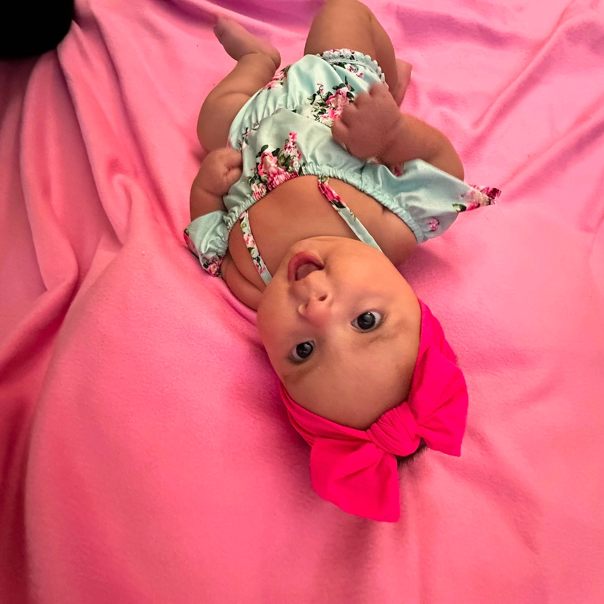 Adeline is registered to the contest to win money with this photo: adorable, baby, bow, child, colorful, cute, expression, floral_clothing, hands, headband, indoors, infant, legs, lying_down, pink_blanket, portrait, romper, skin, soft_texture, wide_eyes