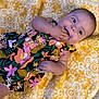 Adeline joined the competition — help win amazing prizes! baby, child, colorful_dress, cute, eyes, fabric, face, fingers, floral_pattern, hand, happy, indoors, infant, lying_down, person, portrait, skin, smiling, texture, yellow_blanket