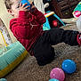 Rene is registered to the contest to win money with this photo: toddler, child, curly_hair, red_hoodie, blue_ball, pink_ball, pastel_colors, carpet, indoor, playroom, toy, play, couch, stuffed_animal, cabinet, floor, clothing, person, casual, fun