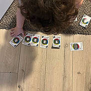 Rene joined the competition — help win amazing prizes! activity, board_game, carpet, child, child_playing, curly_hair, floor, footwear, game, game_cards, hand, indoor, kid, numbered_cards, person, playing, sock, top_view, toy, wooden_floor