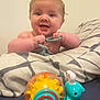Freddie is registered to the contest to win money with this photo: baby, child, toy, snail, blue, yellow, red, blanket, bed, smile, happy, cute, infant, play, hands, face, indoor, person, expression, cheerful