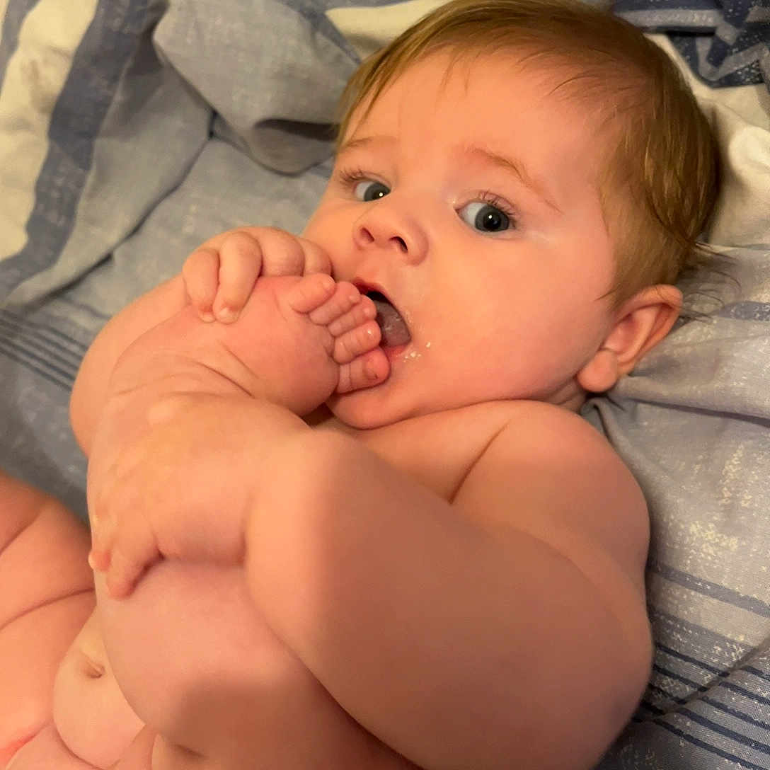 Freddie joined the competition — help win amazing prizes! baby, infant, barefoot, foot, hand, skin, curious, expression, blanket, bed, child, cute, nibbling, closeup, indoors, chubby, person, young, soft, sleepwear