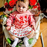 Emmy joined the competition — help win amazing prizes! baby, child, valentines_day, pink_clothing, socks, roses, flower_pattern, cushion, chair, indoor, cute, portrait, infant, sitting, looking_up, white_socks, floor, wooden_floor, pink_skirt, heart_pattern