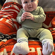Walker joined the competition — help win amazing prizes! baby, child, infant, smile, face, hands, pajamas, socks, blanket, orange, gray, cozy, seated, indoor, cute, happy, portrait, soft, plush, warm