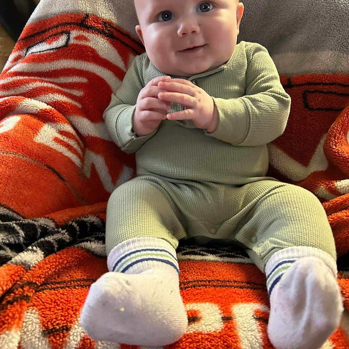 Walker joined the competition — help win amazing prizes! baby, child, infant, smile, face, hands, pajamas, socks, blanket, orange, gray, cozy, seated, indoor, cute, happy, portrait, soft, plush, warm
