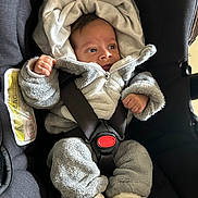 Djaick a rejoint le concours — aidez-le/la à gagner de superbes lots ! baby, infant, newborn, car_seat, harness, buckle, hooded_suit, fleece, cozy, socks, feet, hand, eyes, looking_right, portrait, closeup, indoor, safety_label, clothing, seat_padding