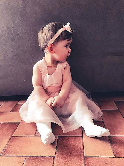 Liselya participe au concours pour gagner de l'argent avec cette photo : baby, baby_toddler_clothing, barefoot, bridal_accessory, child, dress, embellishment, flash_photography, floor, flooring, foot, happy, headpiece, human_leg, jewellery, knee, leg, neck, person, thigh
