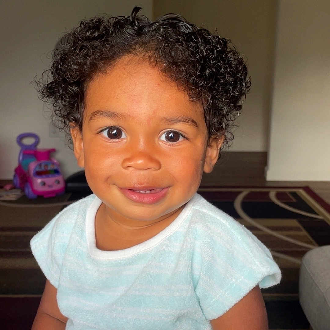 Jalin joined the competition — help win amazing prizes! baby, bright_eyes, carpet, child, close_up, curly_hair, cute, furniture, happy, home, indoor, light_blue_clothing, person, playtime, portrait, sitting, smiling, toddler, toy_car, young_child