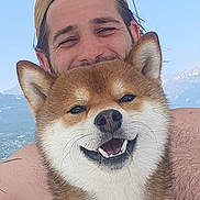 Maïko participe au concours pour gagner de l'argent avec cette photo : dog, shiba_inu, smiling, happy, pet, man, person, cap, outdoor, sky, mountains, water, boat, collar, fur, portrait, nature, summer, vacation, friendship