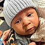 baby, infant, face, hat, knit_hat, blanket, hand, closeup, cute, child, person, warm_clothing, soft_texture, wrapped, indoor, portrait, newborn, skin, expression, holding
