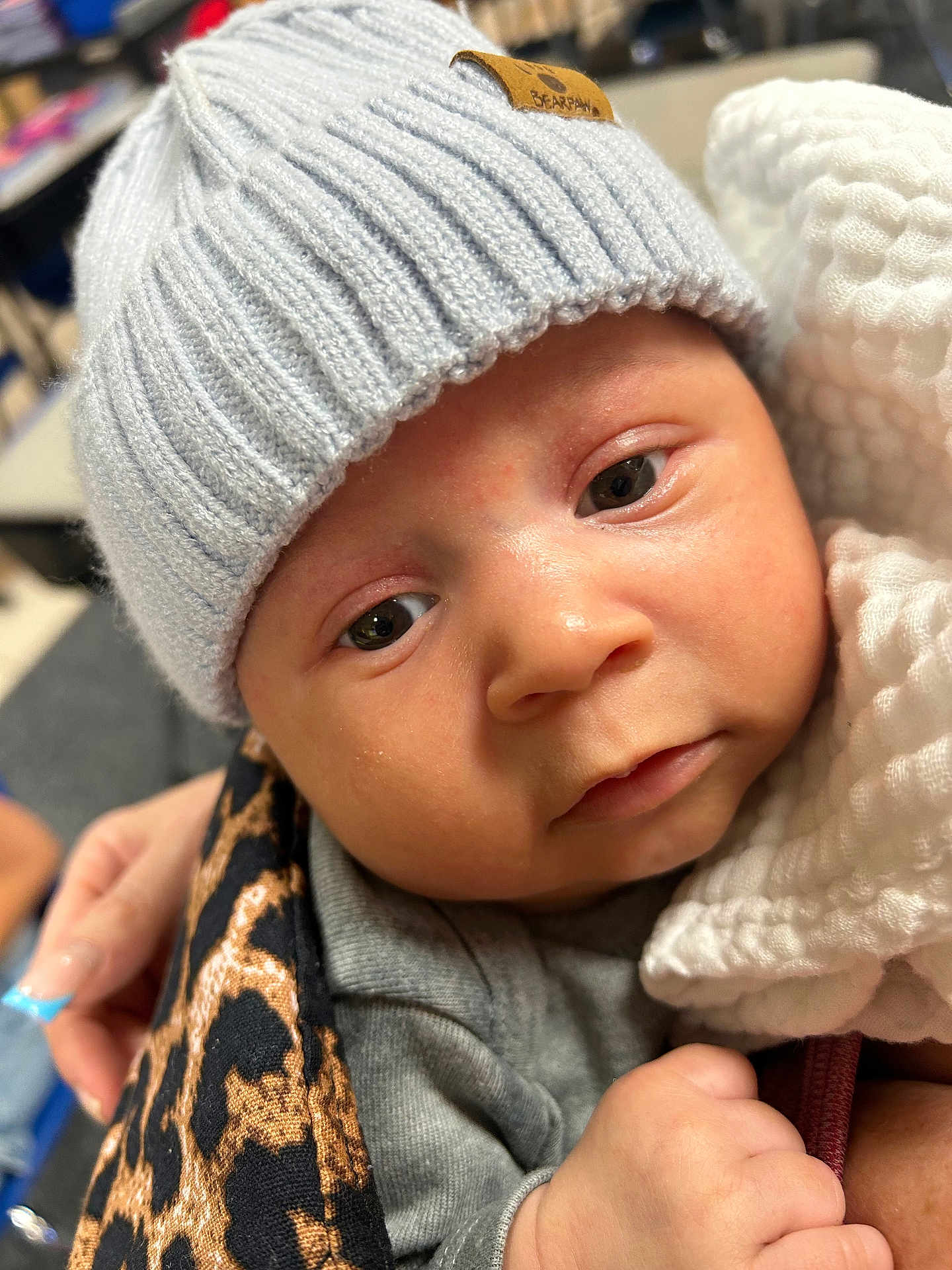 Zakai joined the competition — help win amazing prizes! baby, infant, face, hat, knit_hat, blanket, hand, closeup, cute, child, person, warm_clothing, soft_texture, wrapped, indoor, portrait, newborn, skin, expression, holding