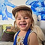 child, toddler, smiling, hat, tank_top, indoor, wall_art, elephant, dolphin, stuffed_animal, teddy_bear, happy, face, person, furniture, colorful, cute, playful, portrait, clothing