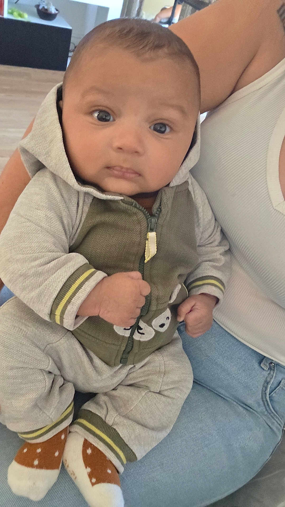 Kiéran a rejoint le concours — aidez-le/la à gagner de superbes lots ! baby, casual, child, closeup, clothing, cozy, cute, expression, face, fist, hoodie, human, indoor, infant, jeans, looking, person, seated, socks, tank_top