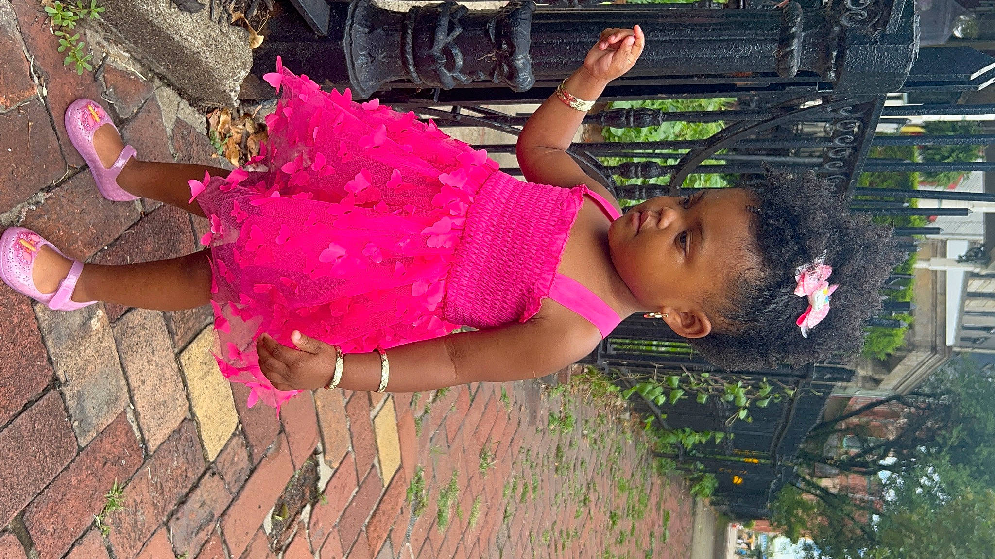 Harley is registered to the contest to win money with this photo: adaptation, black_hair, child, clothing, dress, facial_expression, fun, grass, happy, human_leg, leisure, magenta, pattern, person, pink, sandal, thigh, toddler, trunk, waist