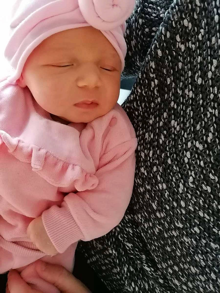 Lya participe au concours pour gagner de l'argent avec cette photo : baby, baby_toddler_clothing, cap, cheek, child, comfort, eye, face, fashion_accessory, headwear, knit_cap, lip, magenta, outerwear, pattern, person, pink, skin, sleeve, textile